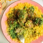 Chicken and pesto meatballs on top of golden rice with pesto on top.