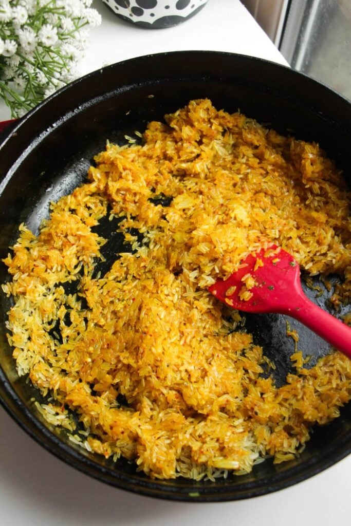 Stirring spices, onion and rice in a large pan.