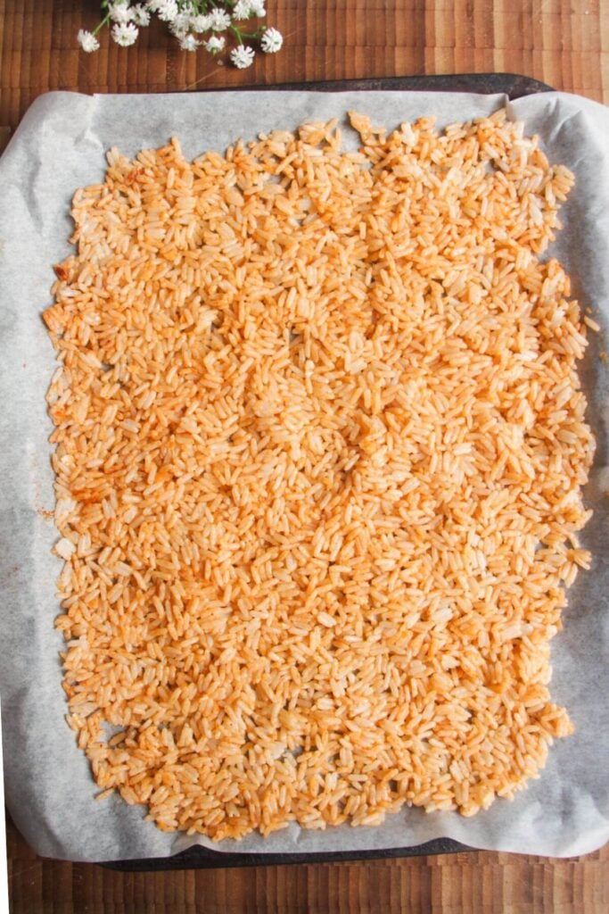 Rice mixed with parmesan and paprika and spread on oven tray.