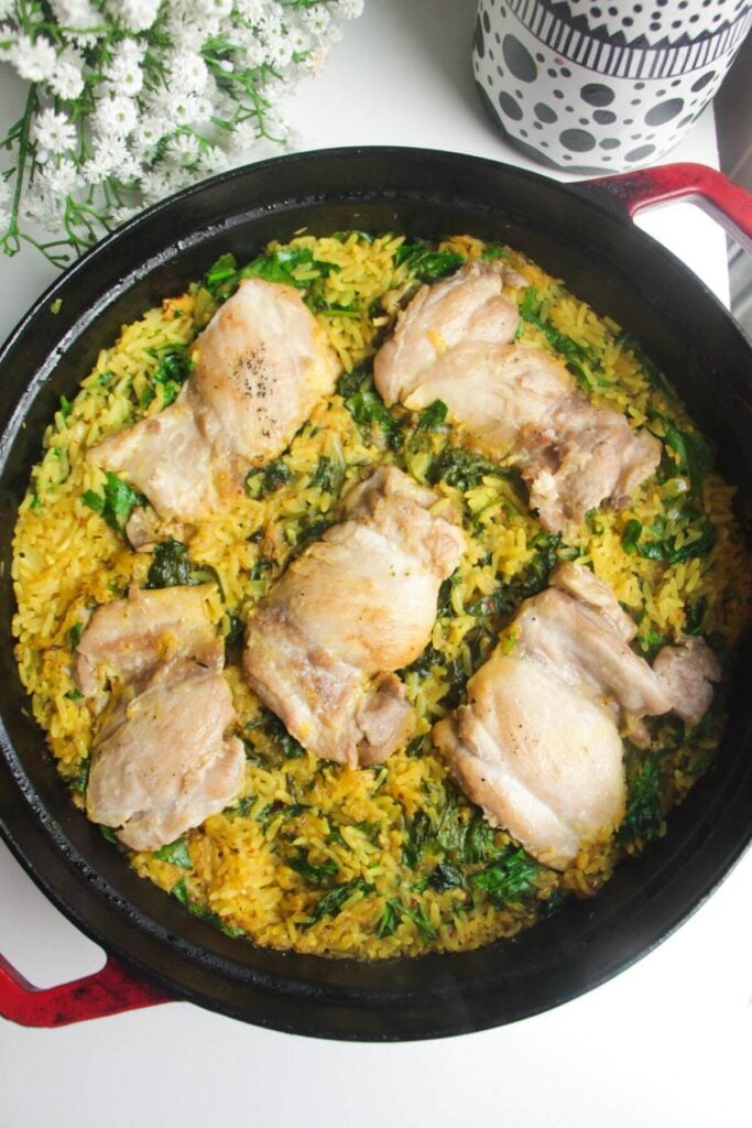 Chicken and golden rice cooked in a large pan.
