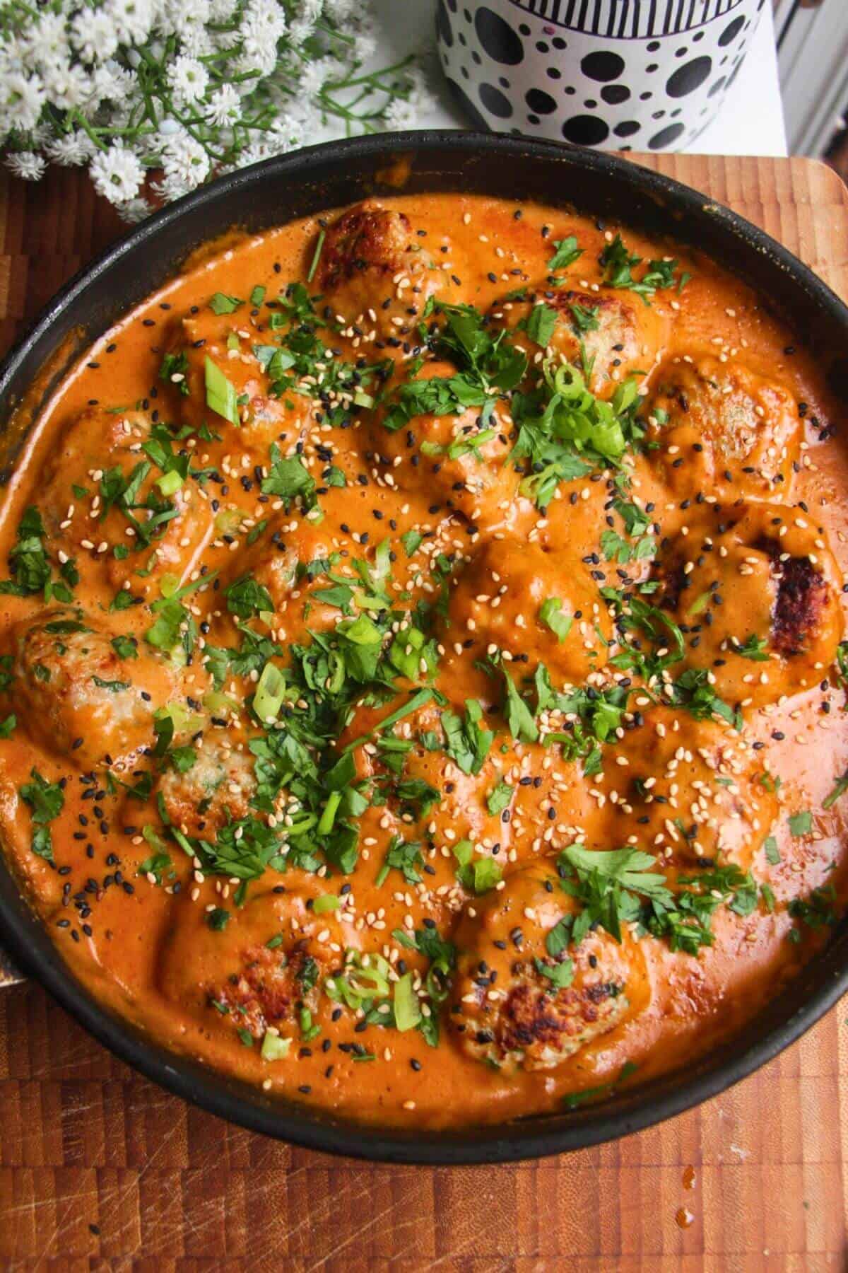 Chicken meatballs in a satay sauce, topped with cilantro and scallions.