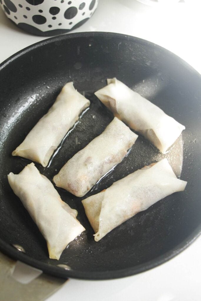 Cheeseburger spring rolls in frying pan.