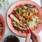 Sweet sour chicken in pink bowls with sauce on the side.