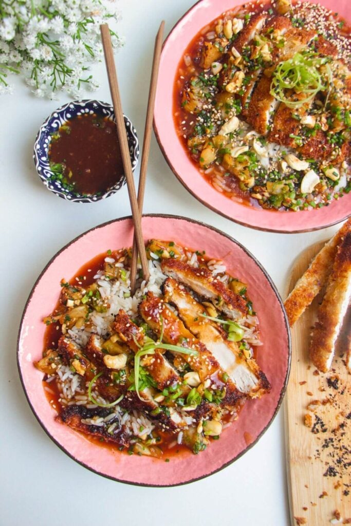 Sweet sour chicken in pink bowls with sauce on the side.