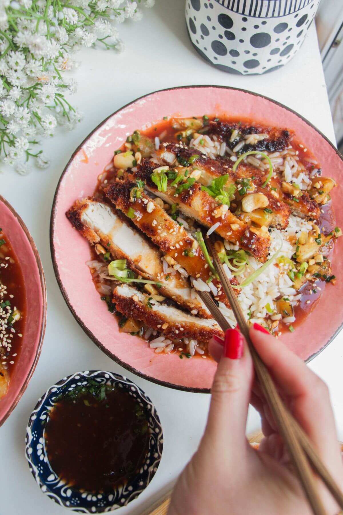 Sweet sour chicken in pink bowls with sauce on the side.