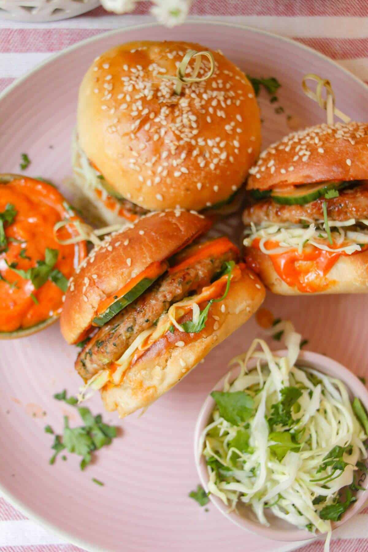 Three dumpling burgers on a pink plate.