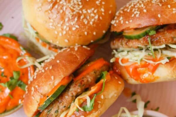 Three dumpling burgers on a pink plate.