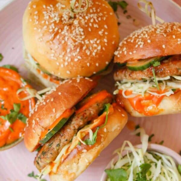 Three dumpling burgers on a pink plate.