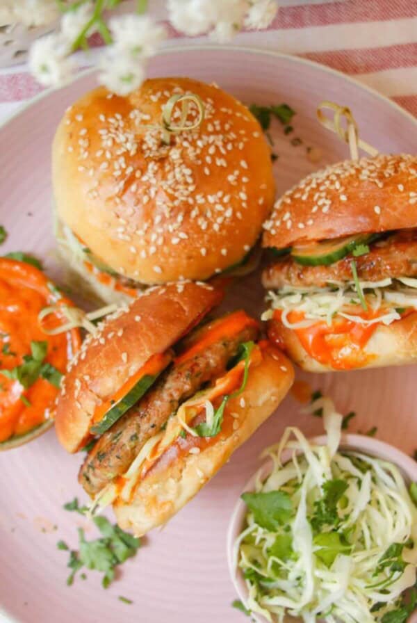 Three dumpling burgers on a pink plate.