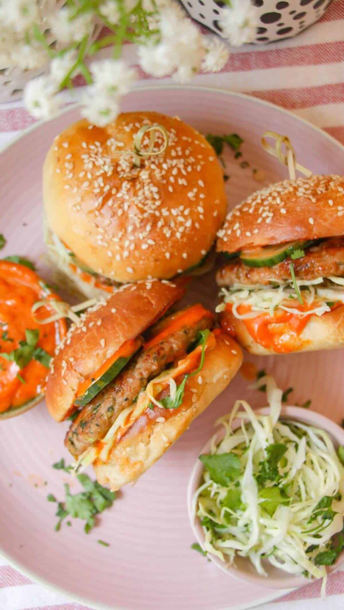 Three dumpling burgers on a pink plate.