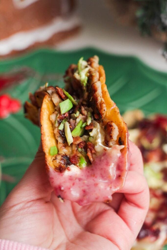 Holding up festive smash taco dipped in cranberry aioli.
