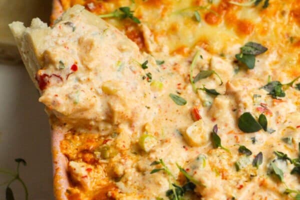 Pita bread dipped into baked dip in a baking dish.