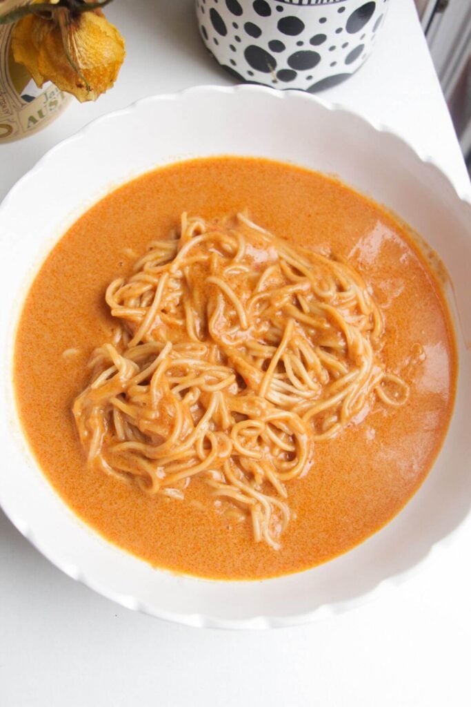 Noodles and peanut satay sauce in a serving bowl.