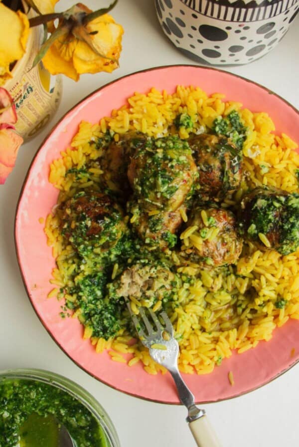Chicken and pesto meatballs on top of golden rice with pesto on top.