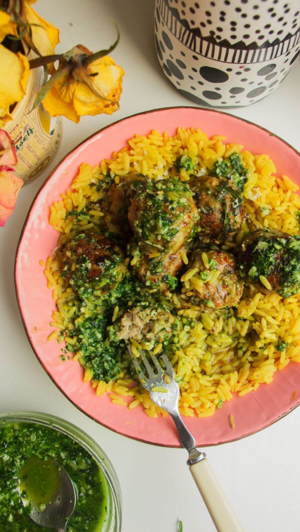 Chicken and pesto meatballs on top of golden rice with pesto on top.