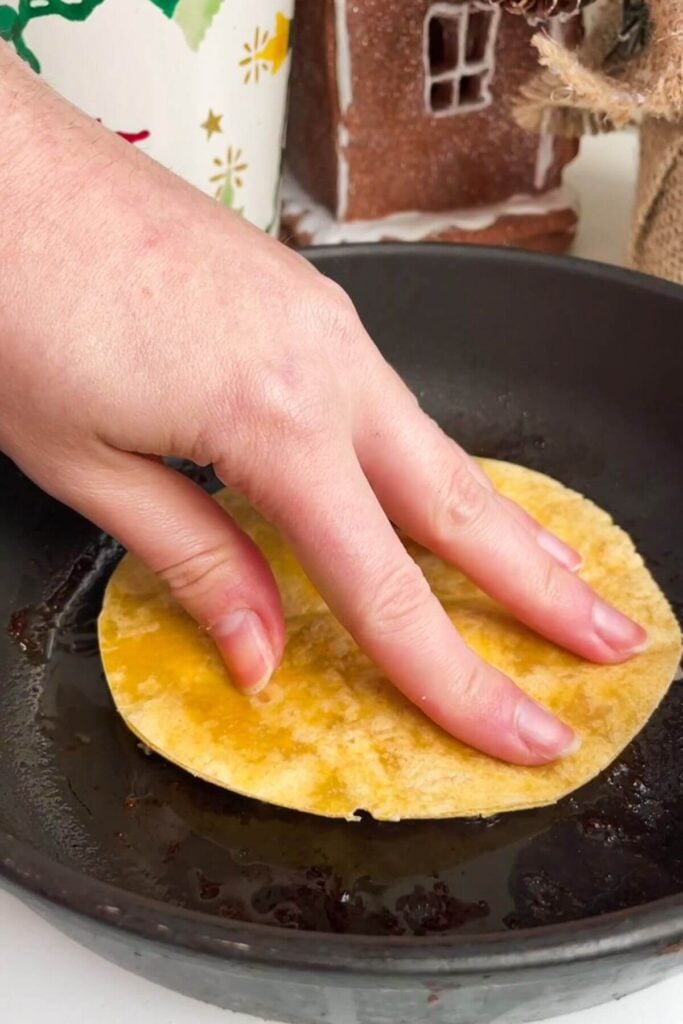 Hand pressing festive smash taco into a small pan.