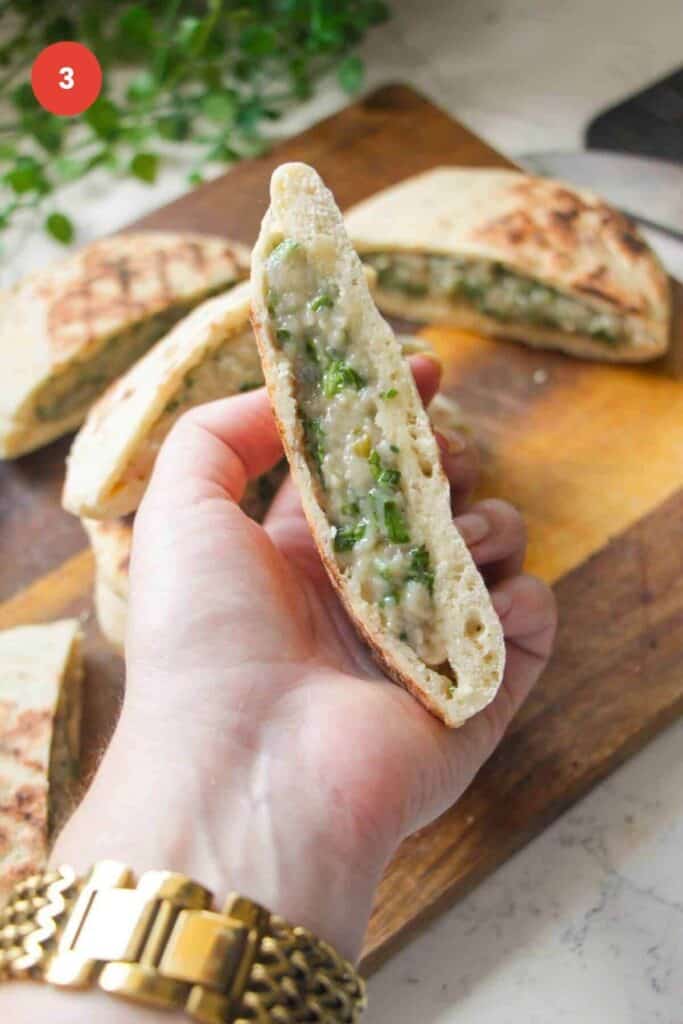 Hand holding flatbread stuffed with dumpling filling.