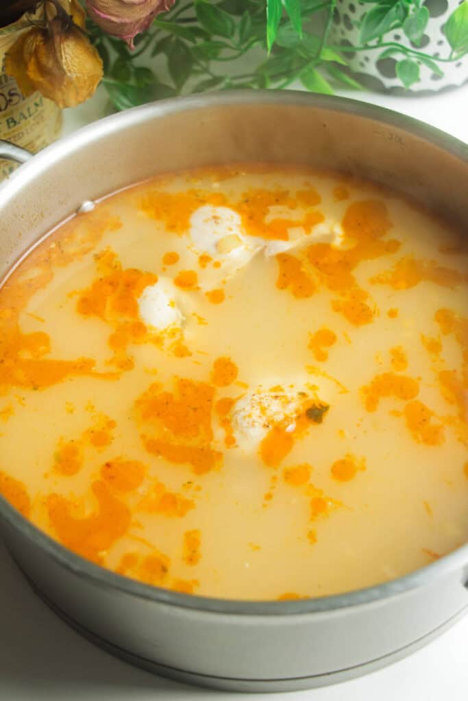 Chicken poached in large pan.