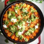 Baked Cowboy Casserole in a large pan with avocado and sour cream on top.