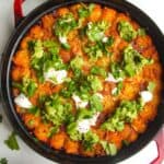 Baked Cowboy Casserole in a large pan with avocado and sour cream on top.