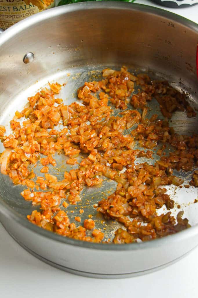 Diced onions cooking in a pan with spices.