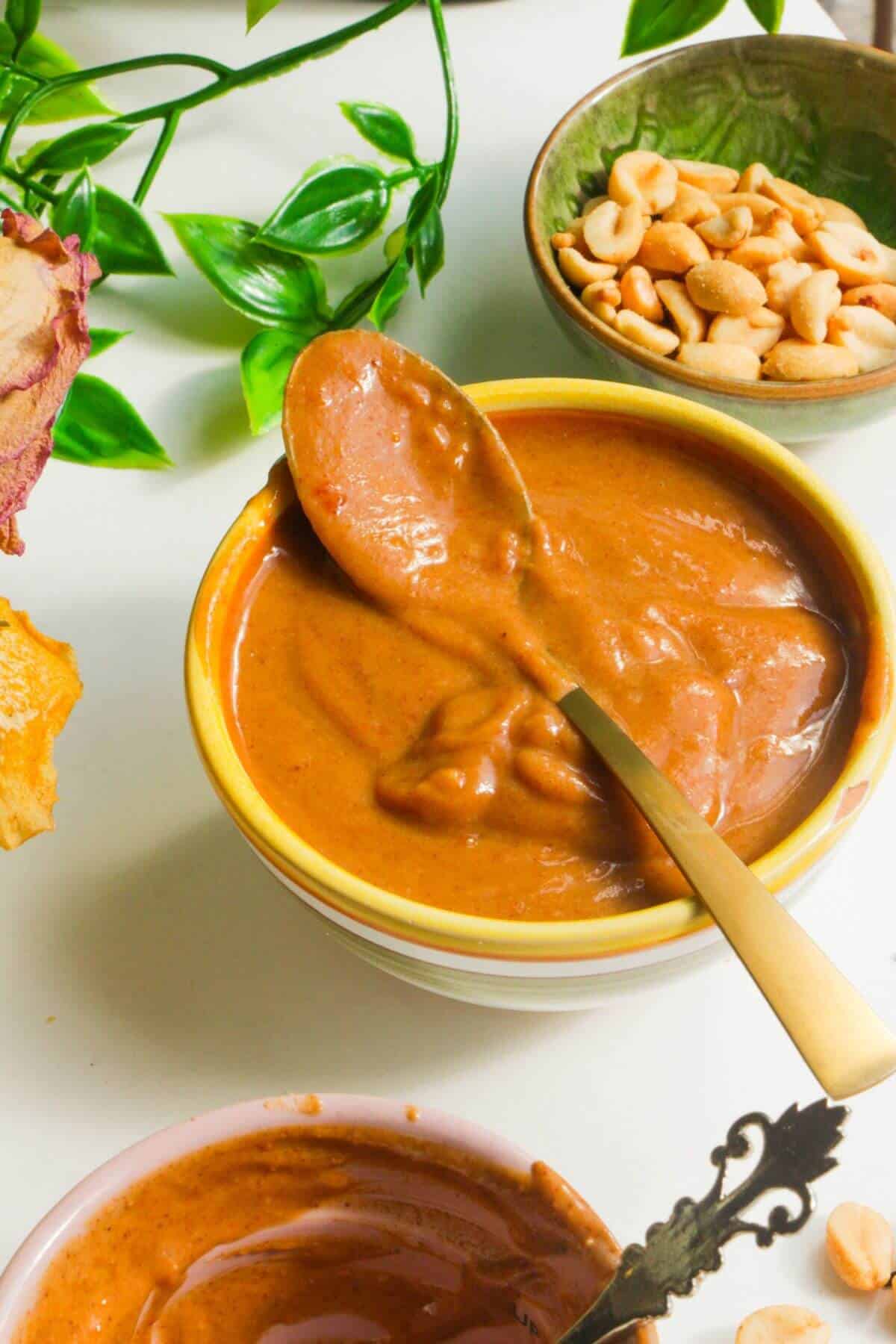 Peanut satay sauce in a small bowl with a spoon.