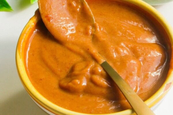 Peanut satay sauce in a small bowl with a spoon.