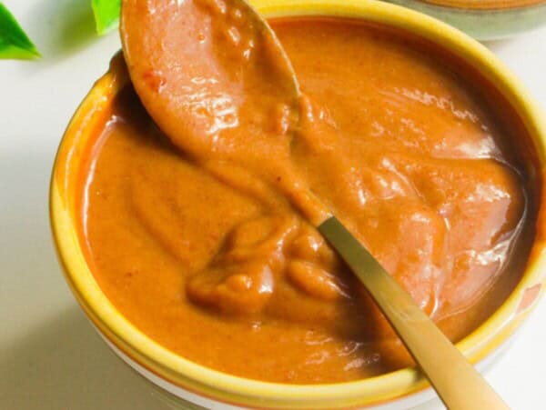 Peanut satay sauce in a small bowl with a spoon.