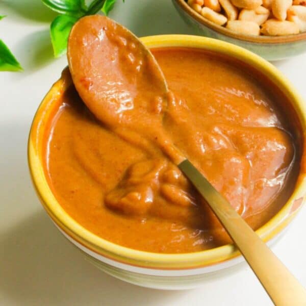 Peanut satay sauce in a small bowl with a spoon.