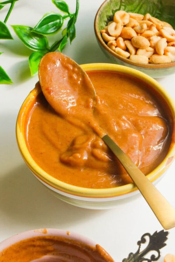 Peanut satay sauce in a small bowl with a spoon.