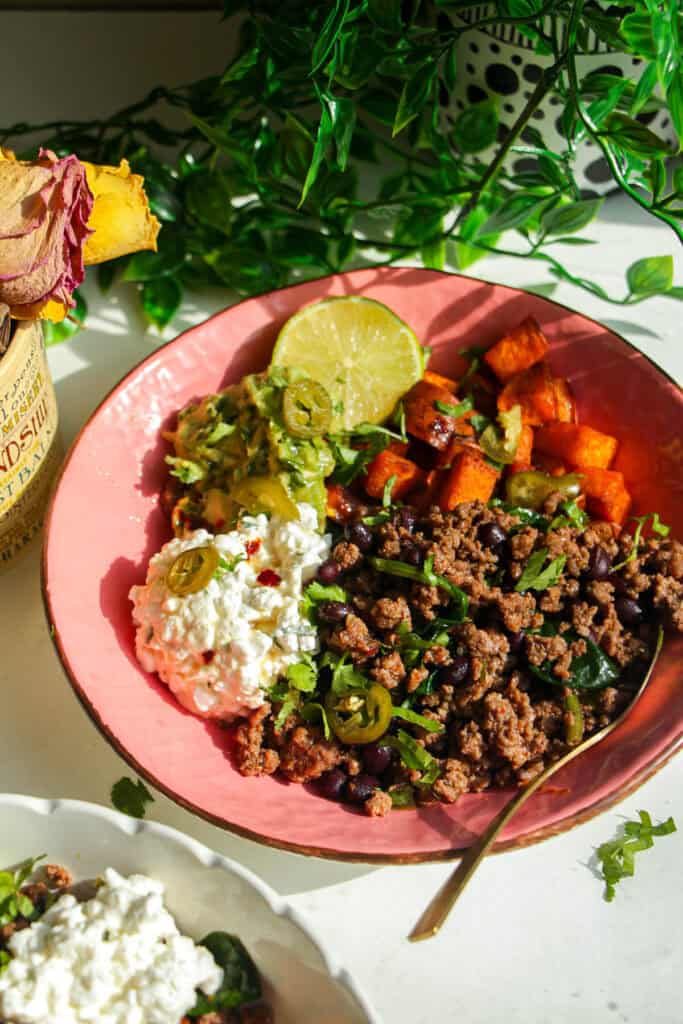 Taco beef protein bowl with lime wedge and golden spoon.