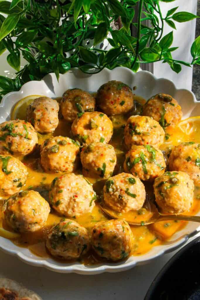 Chicken piccata meatballs in a white scalloped bowl.