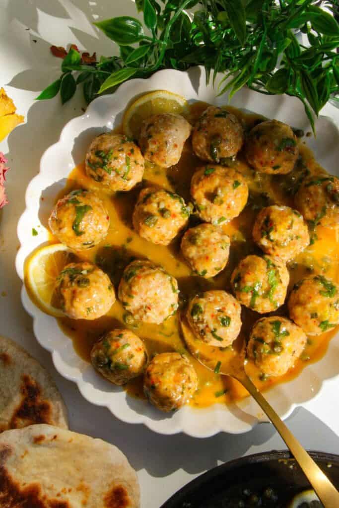 Chicken piccata meatballs in a white scalloped bowl.