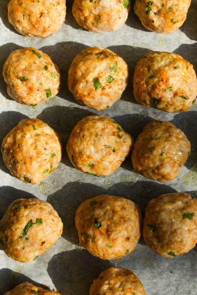 Cooked chicken piccata meatballs on an oven tray.