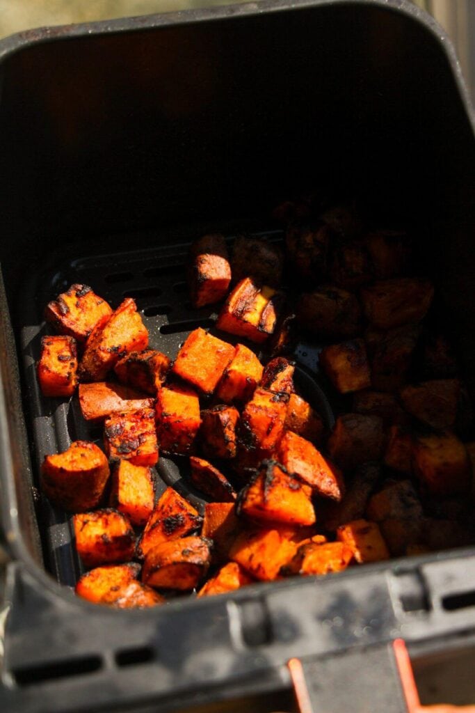 Cooked sweet potato cubes in an air fryer basket.
