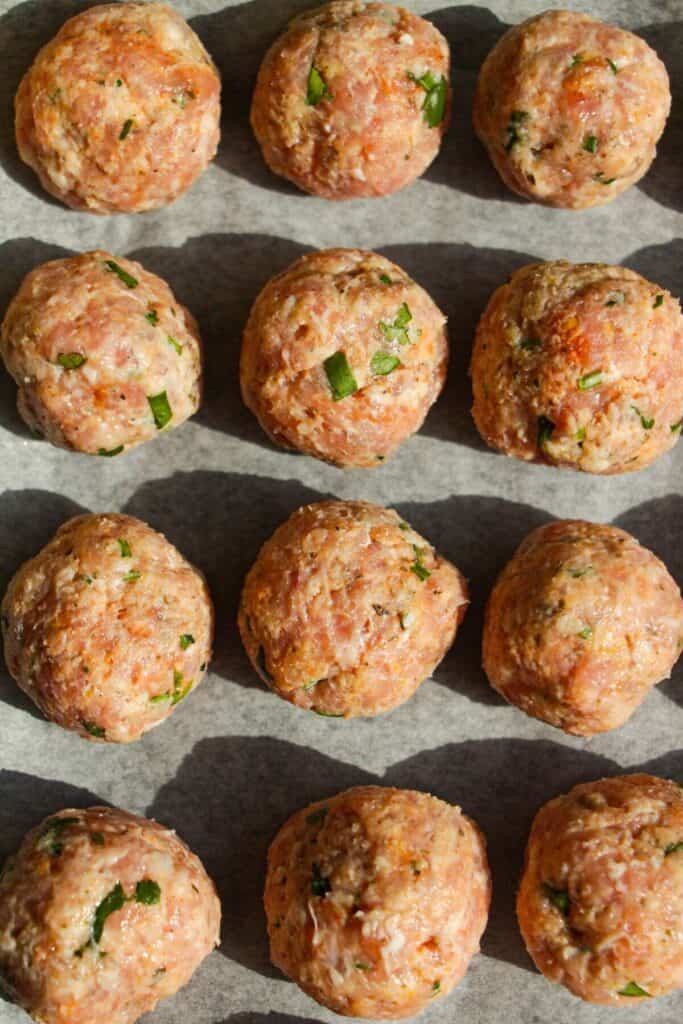 Chicken piccata meatballs on a lined oven tray.