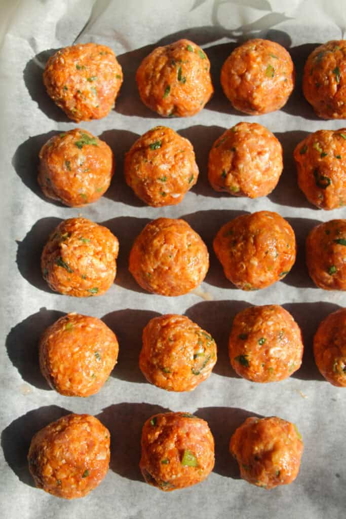 Gochujang chicken meatballs on a lined oven tray.