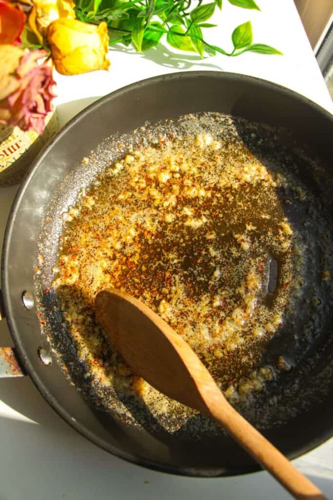 Stirring garlic in butter in a pan.