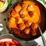 Gochujang chicken meatballs mixed with coconut gochujang sauce in a pan.