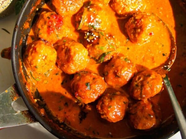 Gochujang chicken meatballs mixed with coconut gochujang sauce in a pan.