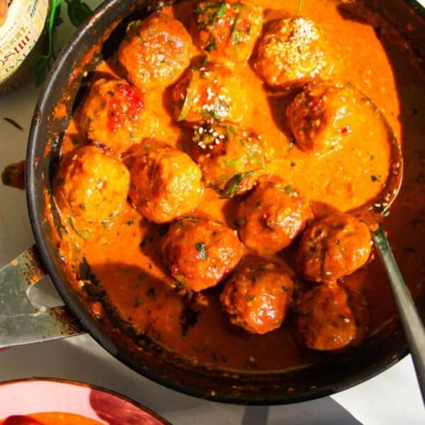 Gochujang chicken meatballs mixed with coconut gochujang sauce in a pan.