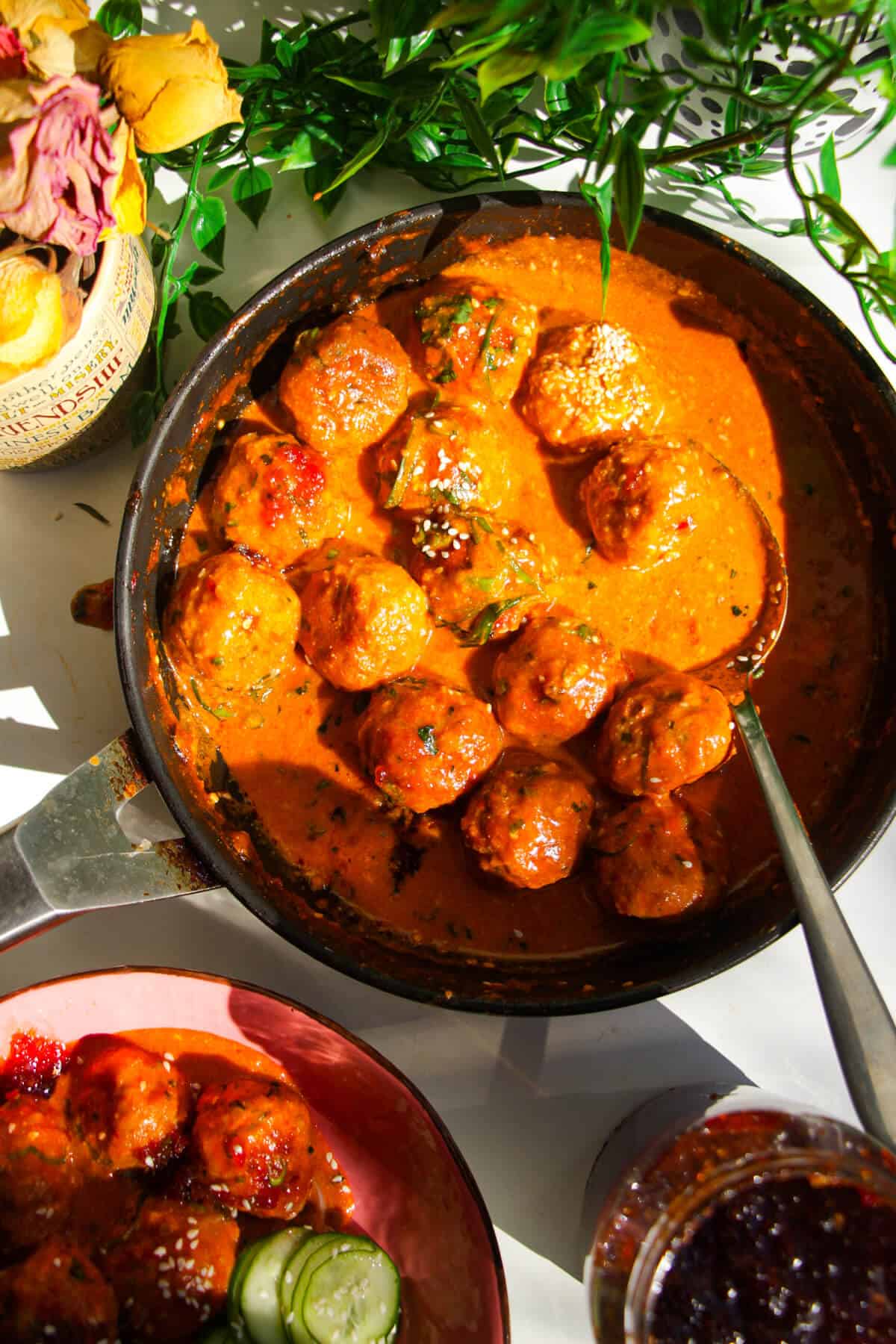 Gochujang chicken meatballs mixed with coconut gochujang sauce in a pan.