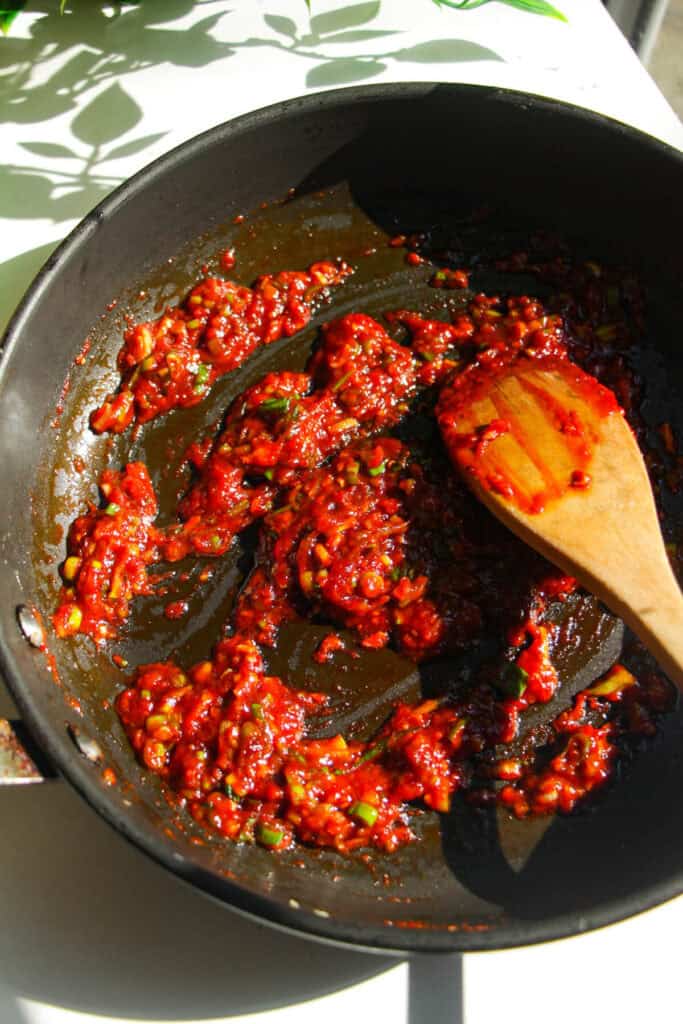 Gochujang paste mixed with scallions in a pan.