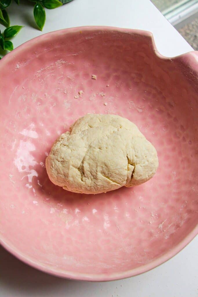 Bagel dough mixed in a pink bowl.