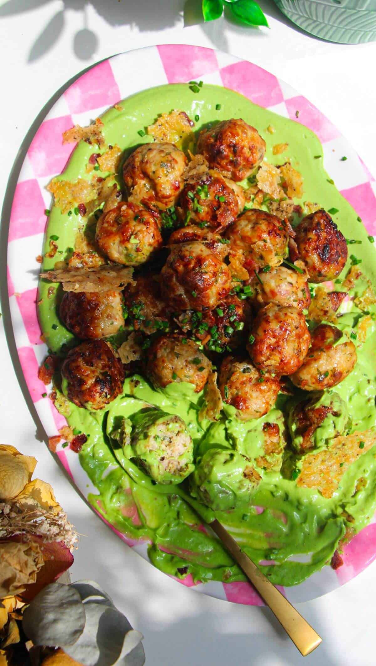 Chicken Caesar meatballs on a pink and white plate.