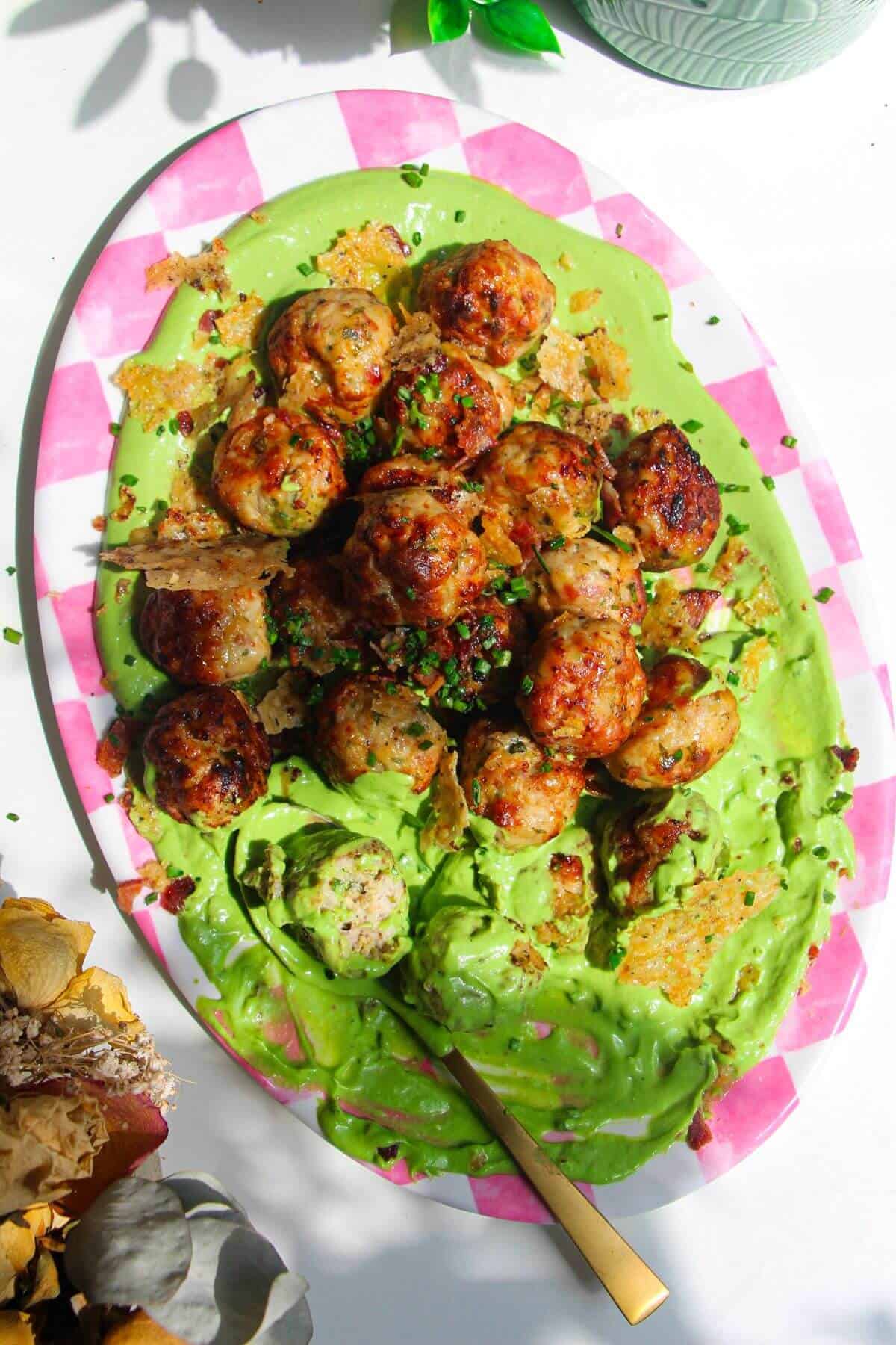 Chicken Caesar meatballs on a pink and white plate.