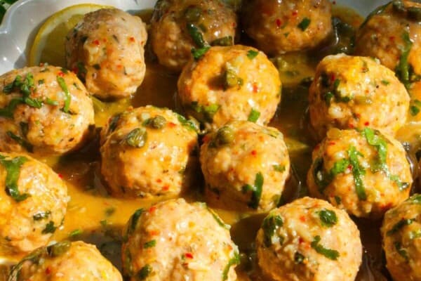 Chicken piccata meatballs in a white scalloped bowl.