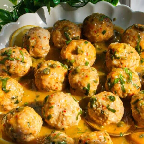 Chicken piccata meatballs in a white scalloped bowl.