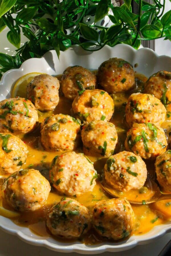 Chicken piccata meatballs in a white scalloped bowl.