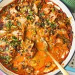 Baked dumplings in satay sauce in a skillet with chili oil on top.